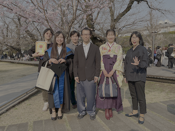 桜の木の前に並ぶ学生と先生